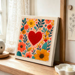 Red heart surrounded by colourful blooms punch needle artwork displayed on a table