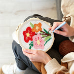 Creating handmade red, pink and orange floral bouquet punch needle artwork