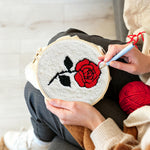 Creating handmade red rose on white background punch needle artwork