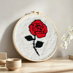 Red rose on white background punch needle artwork displayed on a table