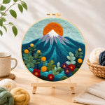Finished red sun over snowy peaks needle felting displayed on a wooden easel