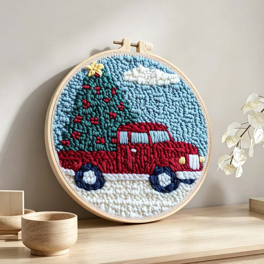Red truck hauling christmas tree punch needle artwork displayed on a table