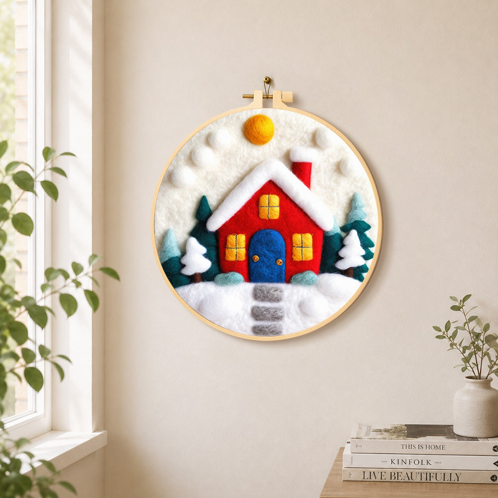 Red winter house with blue door needle felt wall art displayed in a bright home interior