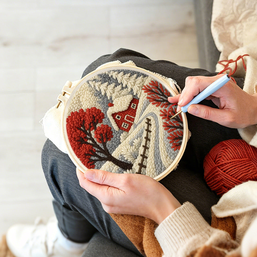 Creating handmade red winter tree and snowy cottage punch needle artwork