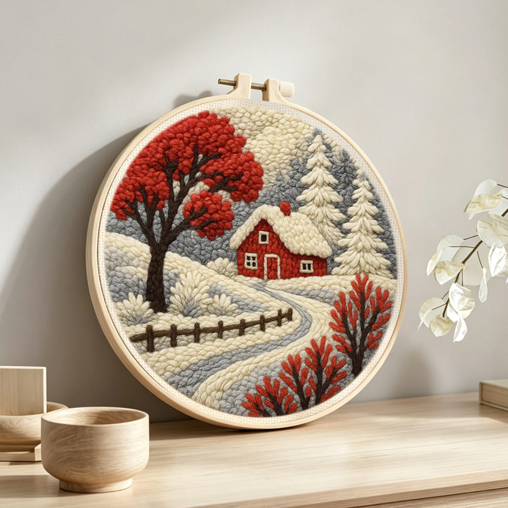 Red winter tree and snowy cottage punch needle artwork displayed on a table
