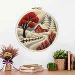 Finished red winter tree and snowy cottage artwork displayed on a wall