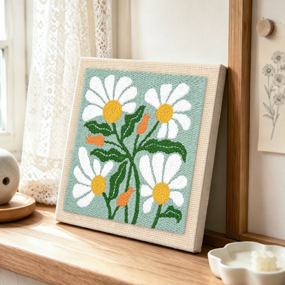 Sage green daisies punch needle artwork displayed on a table
