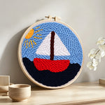 Sailboat on the sea under the sunlight punch needle artwork displayed on a table