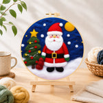 Finished santa and christmas tree needle felting displayed on a wooden easel