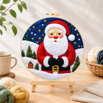 Finished santa with mini village needle felting displayed on a wooden easel