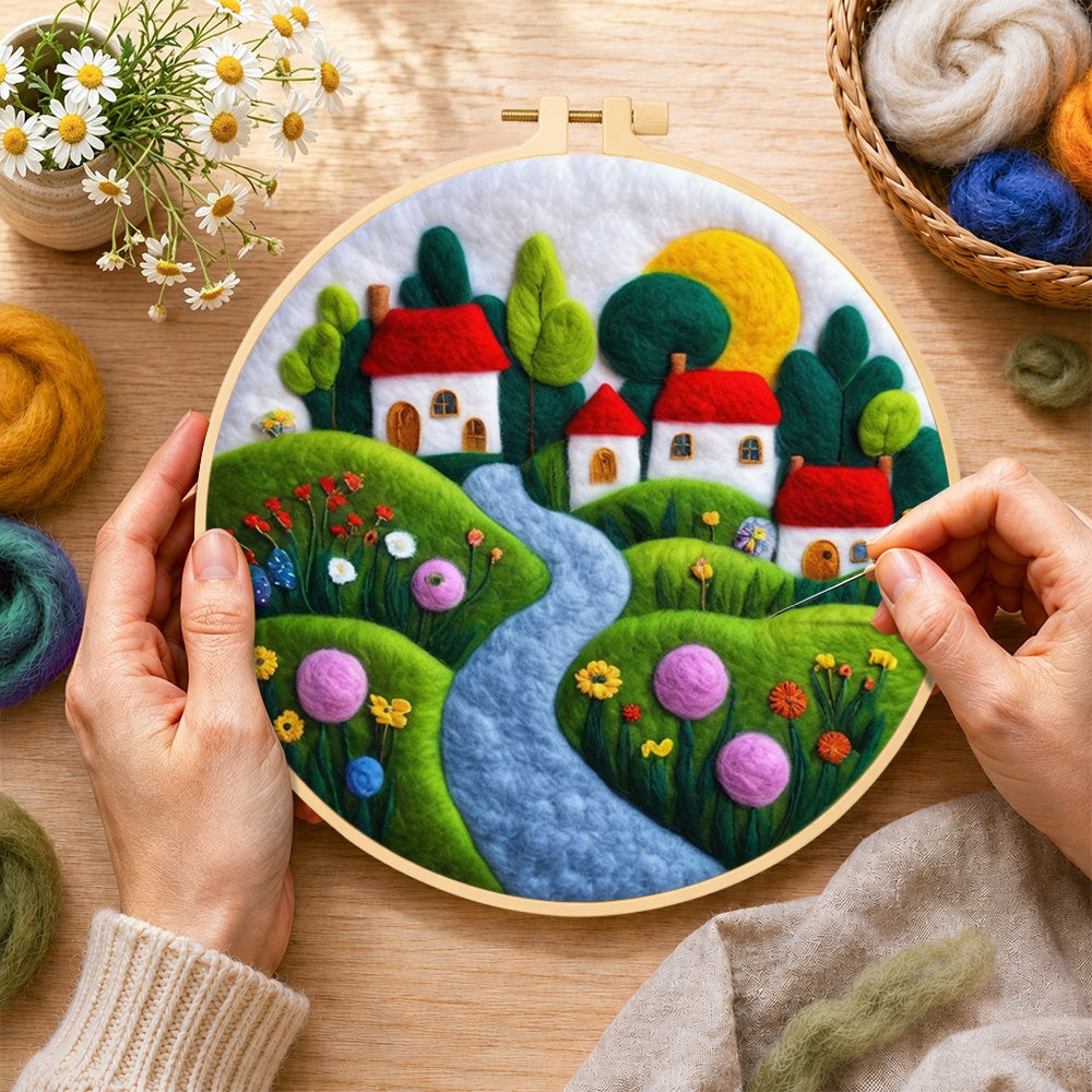 Creating the serene blue river and red roof village wool painting by hand with a felting needle