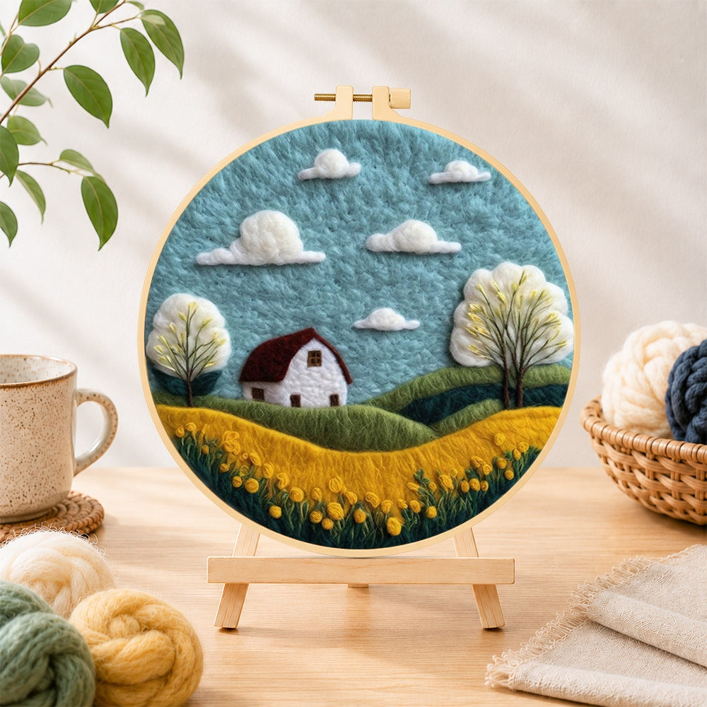 Finished serene blue sky and golden field needle felting displayed on a wooden easel