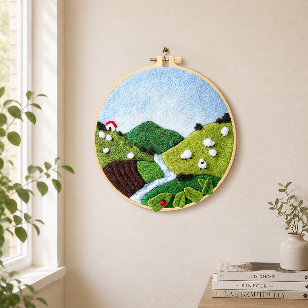 sheep on the green hillside needle felt wall art displayed in a bright home interior