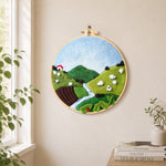 sheep on the green hillside needle felt wall art displayed in a bright home interior