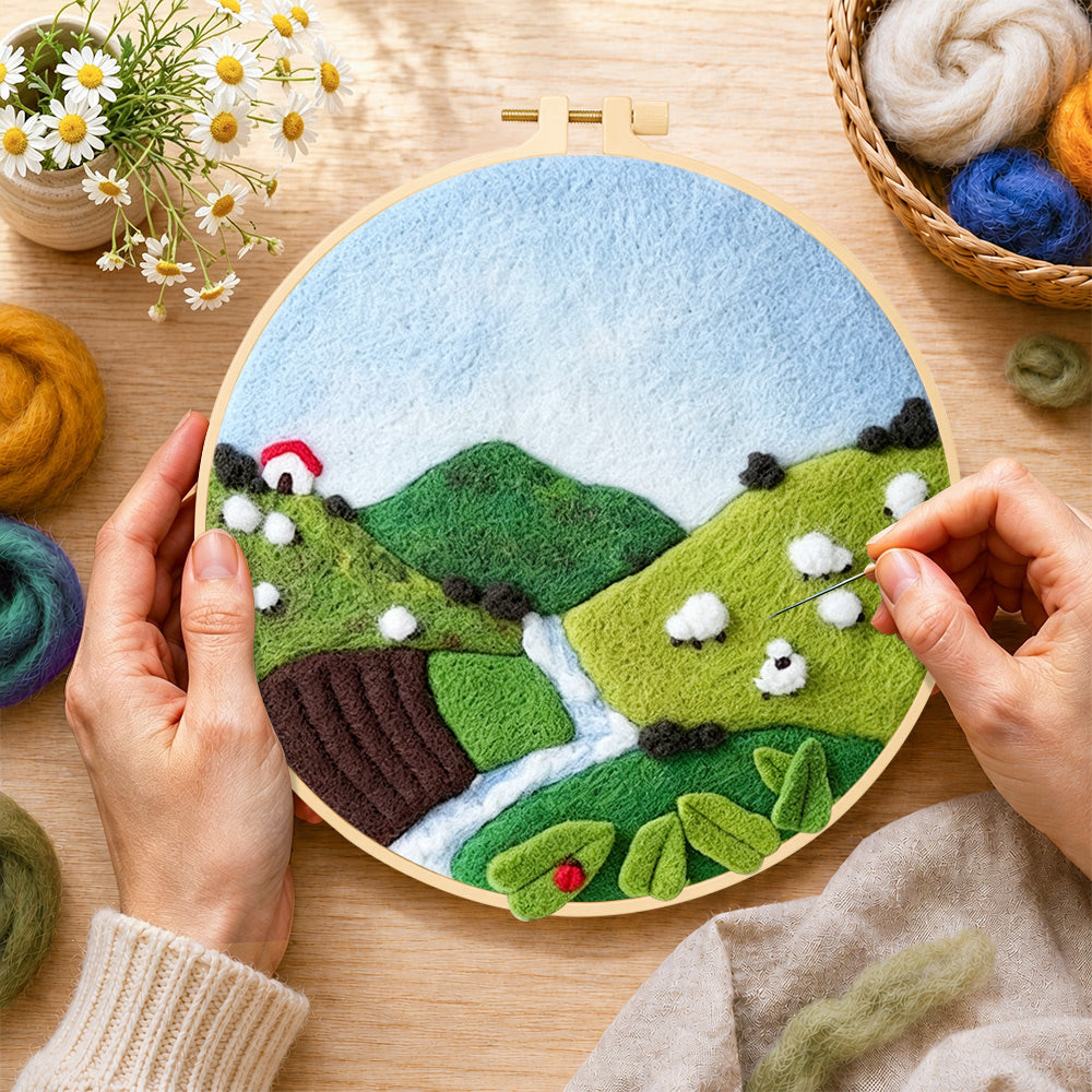 Creating the sheep on the green hillside wool painting by hand with a felting needle