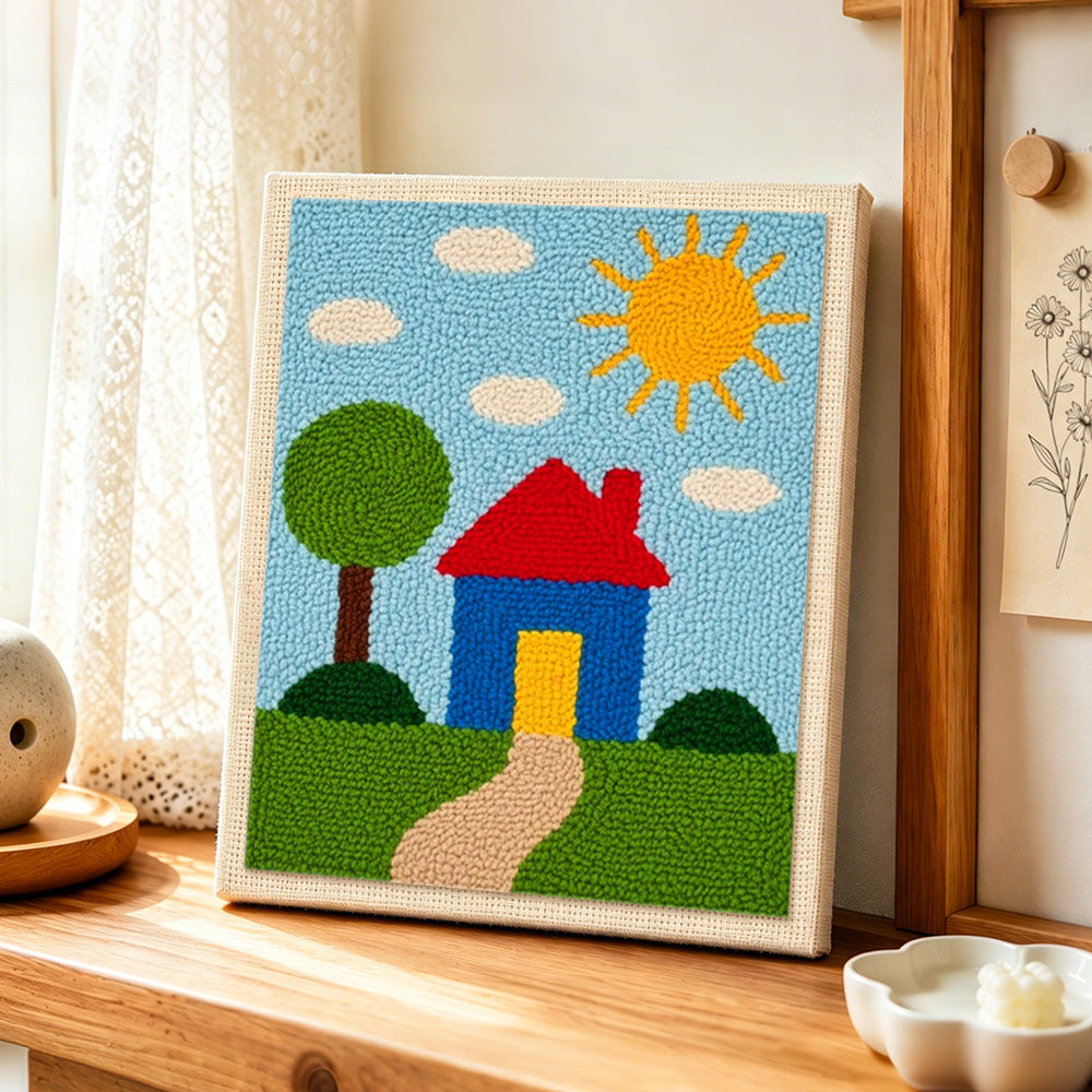 Simple sunny house and green tree punch needle artwork displayed on a table