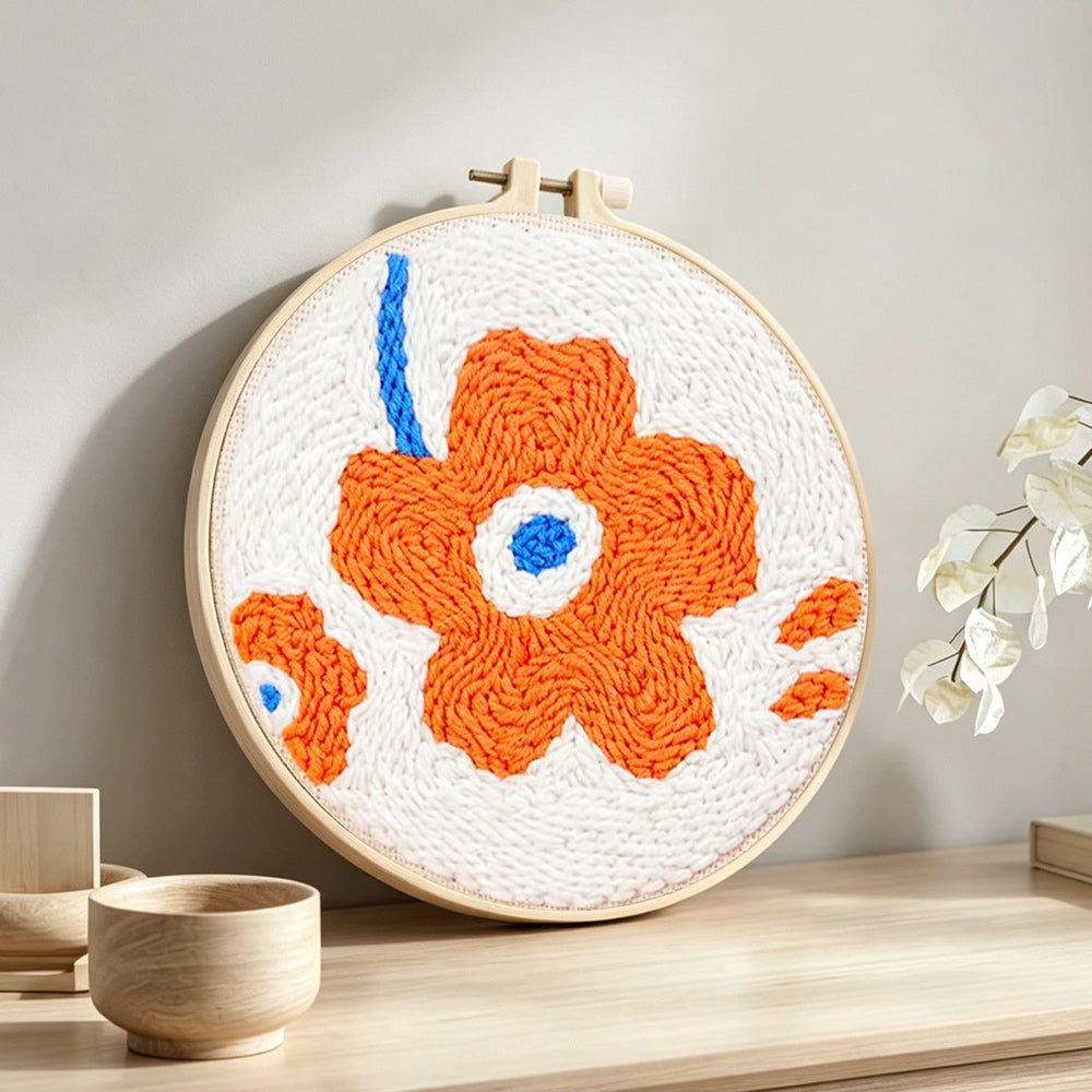 Single orange flower punch needle artwork displayed on a table