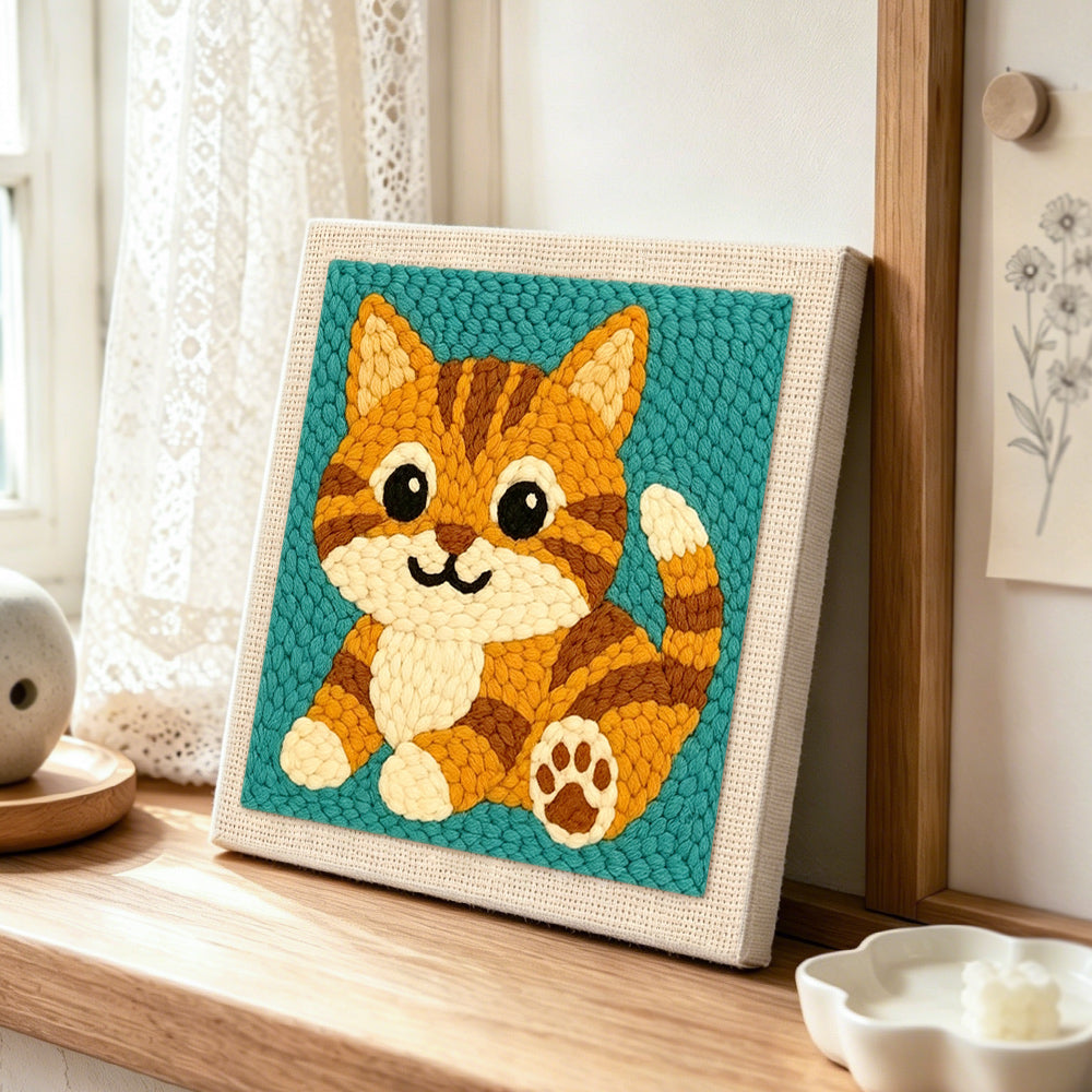 Sitting orange tabby cat punch needle artwork displayed on a table