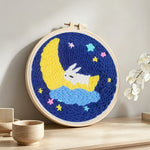 Sleeping bunny on crescent moon and stars punch needle artwork displayed on a table