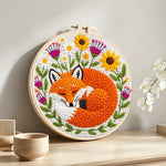 Sleeping fox among the flowers punch needle artwork displayed on a table