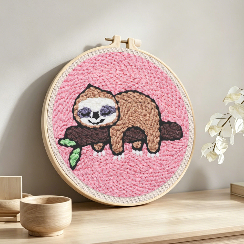 Sleeping sloth on tree branch punch needle artwork displayed on a table