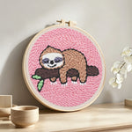 Sleeping sloth on tree branch punch needle artwork displayed on a table