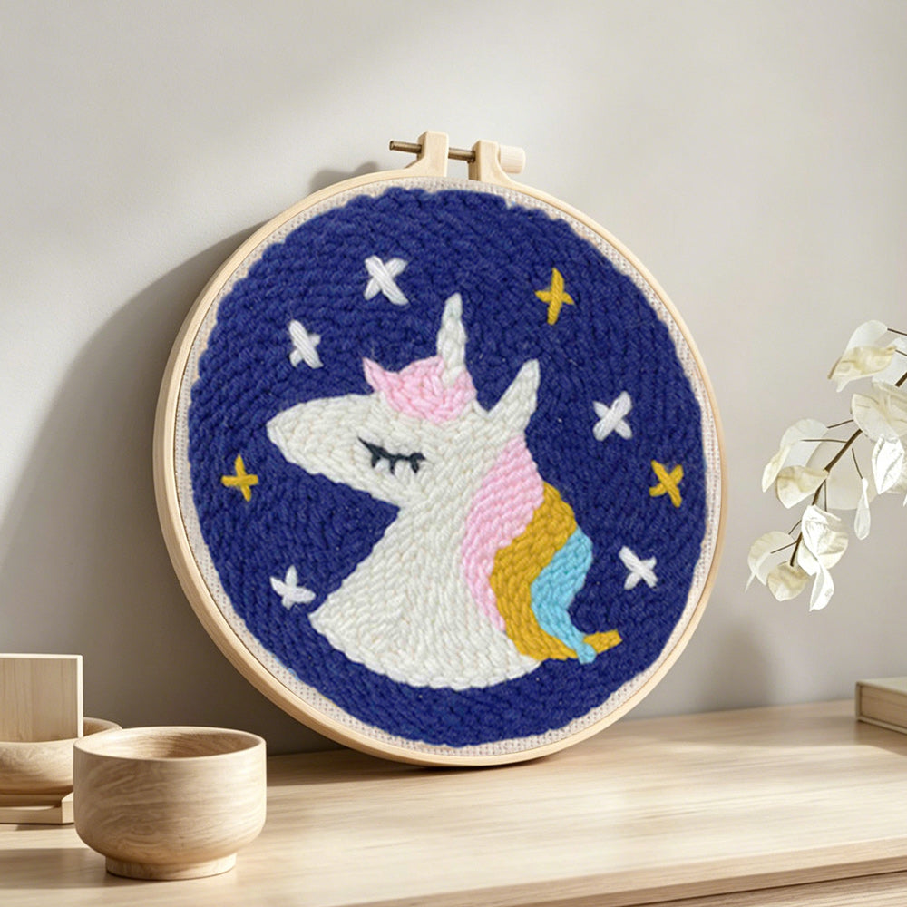 Sleeping unicorn under stars punch needle artwork displayed on a table