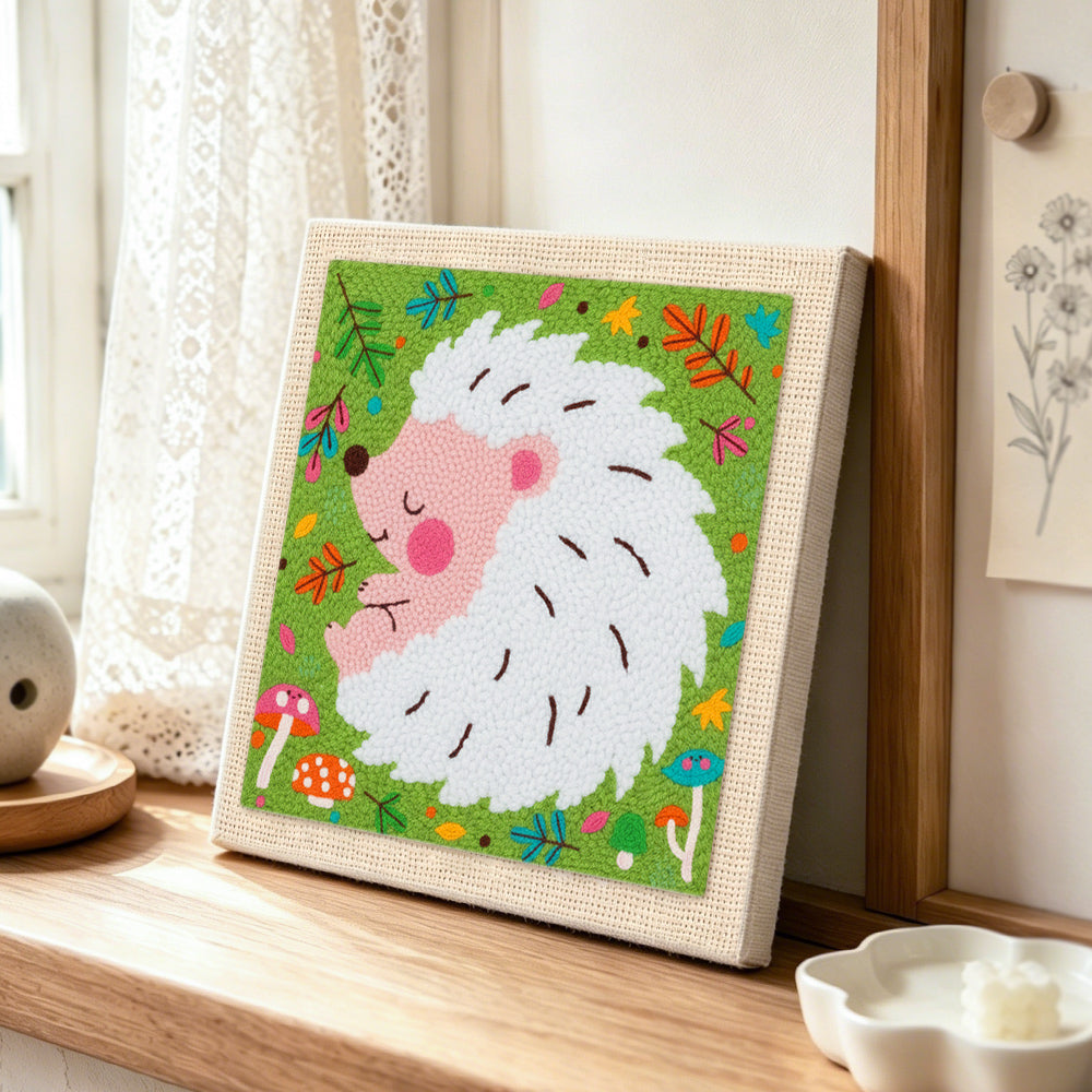 Sleeping white hedgehog punch needle artwork displayed on a table