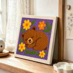 Sleepy bear with flowers punch needle artwork displayed on a table
