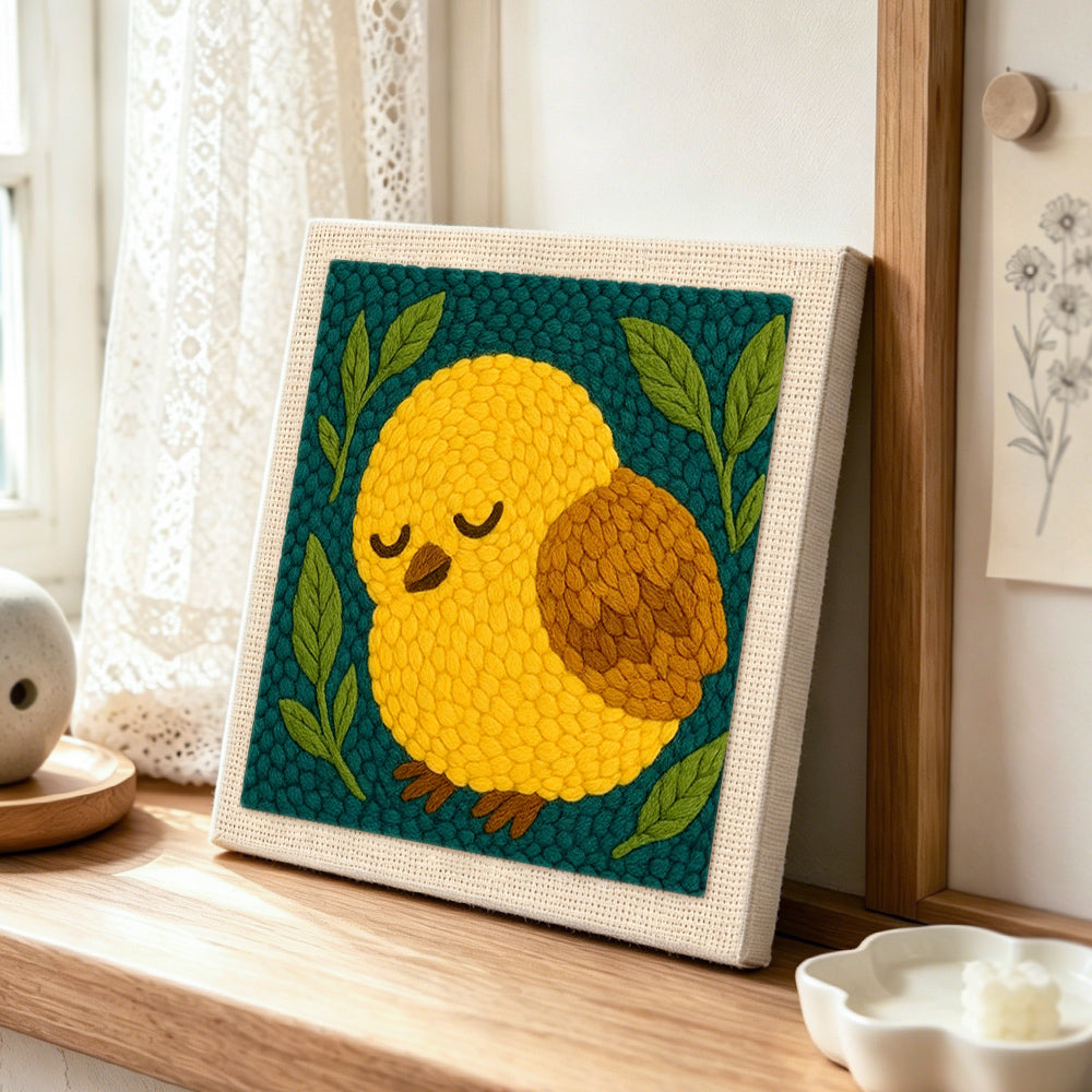 Sleepy yellow bird punch needle artwork displayed on a table