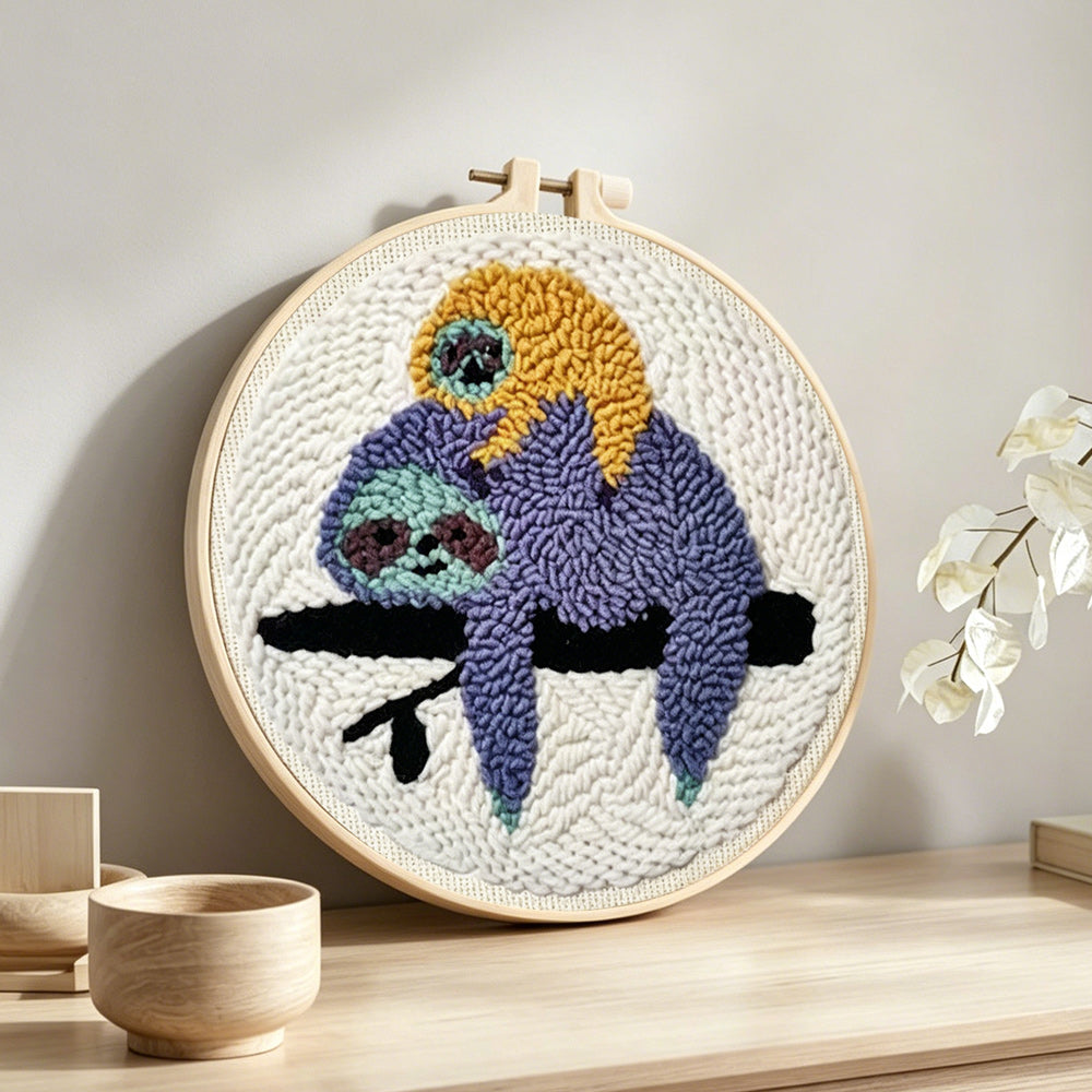 Sloths resting on tree branch punch needle artwork displayed on a table