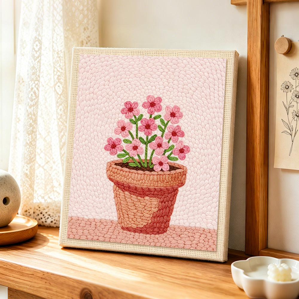 Small pink flowers in pot punch needle artwork displayed on a table