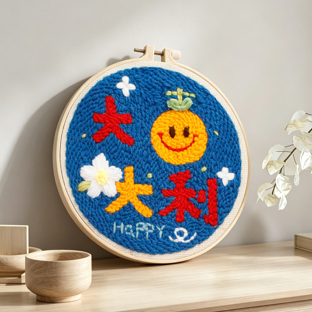 Smiley orange with "best of luck" text punch needle artwork displayed on a table