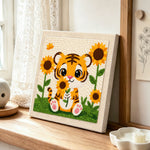Smiling baby tiger with sunflowers punch needle artwork displayed on a table