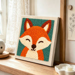 Smiling fox portrait punch needle artwork displayed on a table