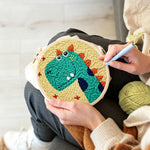 Creating handmade smiling green dinosaur punch needle artwork