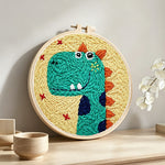 Smiling green dinosaur punch needle artwork displayed on a table