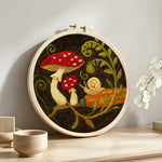 Snail and mushroom punch needle artwork displayed on a table