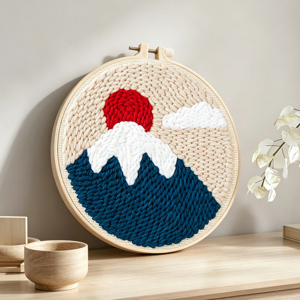 Snow-capped mountain at sunrise punch needle artwork displayed on a table
