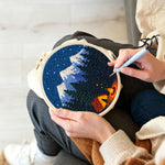 Creating handmade snow-capped mountains, dark forest and campfire punch needle artwork