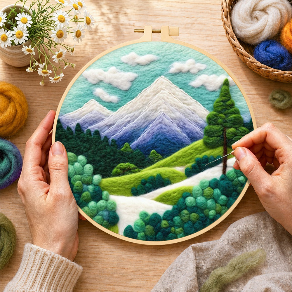 Creating the snow-capped peaks and green trees wool painting by hand with a felting needle