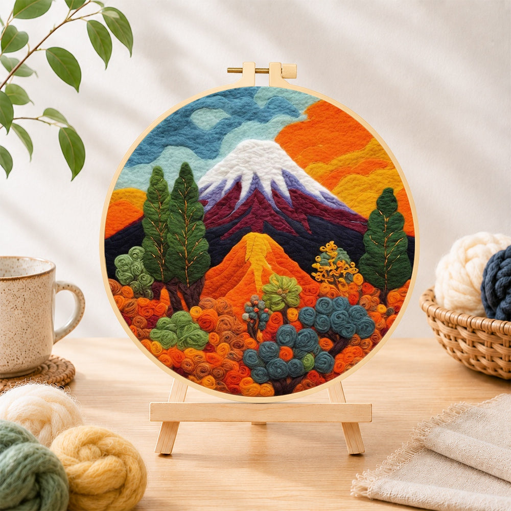 Finished snow-capped volcano and lush plants needle felting displayed on a wooden easel