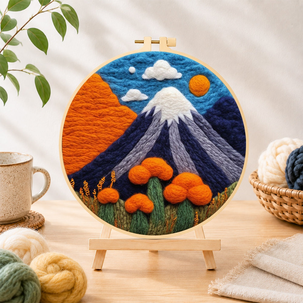 Finished snow-capped volcano needle felting displayed on a wooden easel