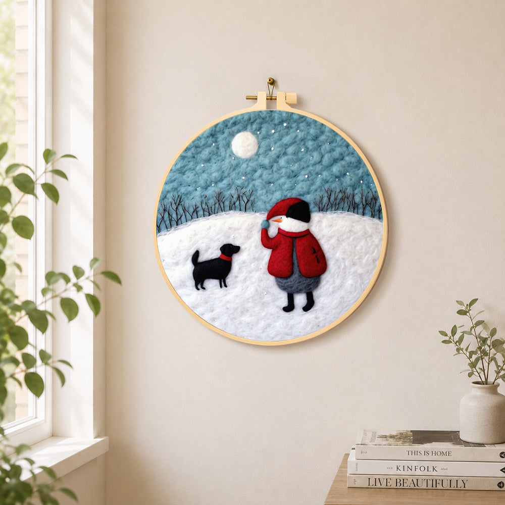 Snowman and black dog in the snow needle felt wall art displayed in a bright home interior