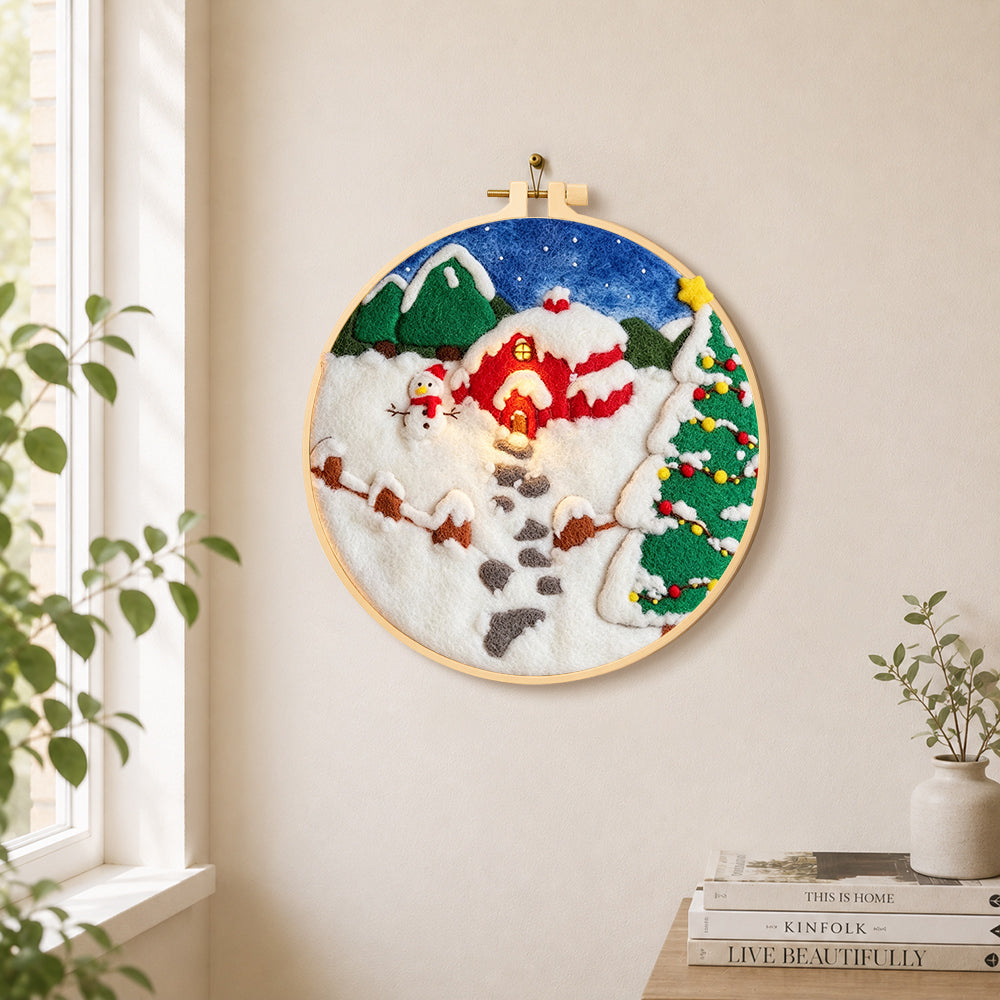 Snowman and christmas tree red cabin needle felt wall art displayed in a bright home interior