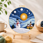 Finished snowman and swirling starry night sky needle felting displayed on a wooden easel