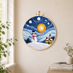 Snowman and swirling starry night sky needle felt wall art displayed in a bright home interior