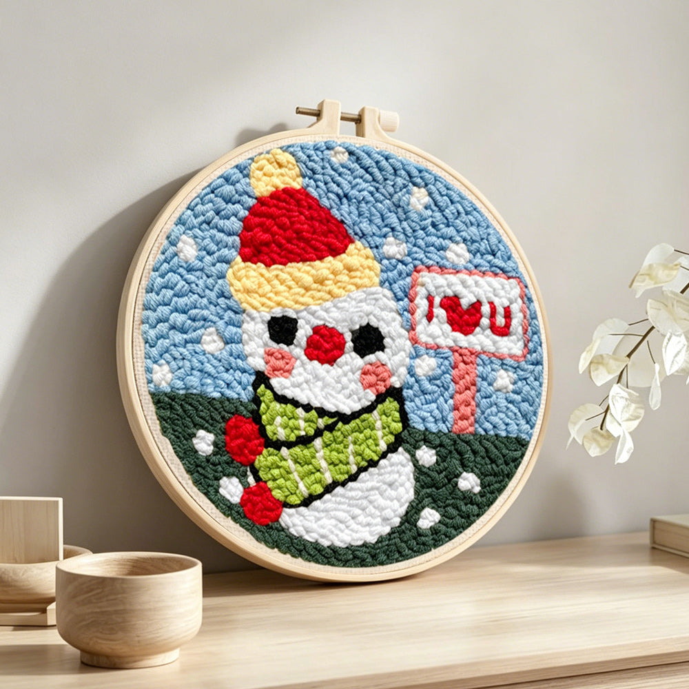 Snowman with “i love you” sign punch needle artwork displayed on a table