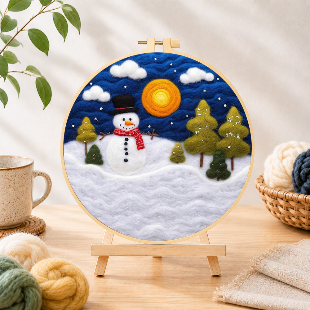 Finished snowman with red scarf and pine trees needle felting displayed on a wooden easel