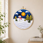 Snowman with red scarf and pine trees needle felt wall art displayed in a bright home interior